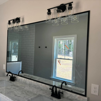 Modern bathroom vanity with large black-framed mirror, double sinks, and wall lights