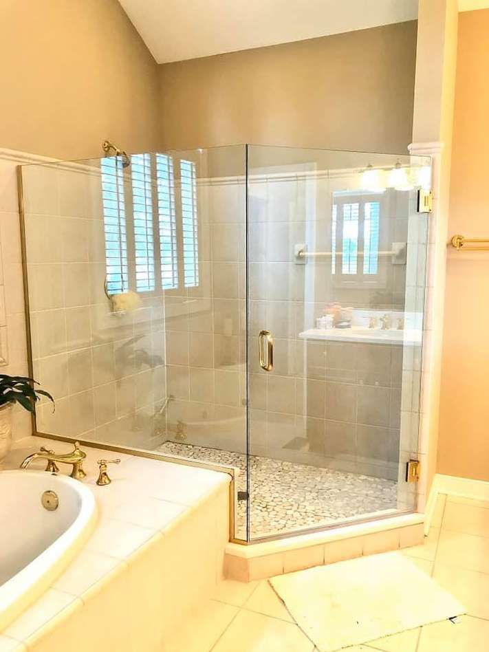 Bright bathroom with glass-enclosed shower, beige tile, and a white sink vanity.
