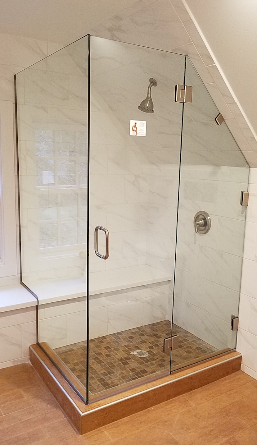 Glass walk-in shower with chrome fixtures, white tile walls, and pebble-stone floor in a bathroom