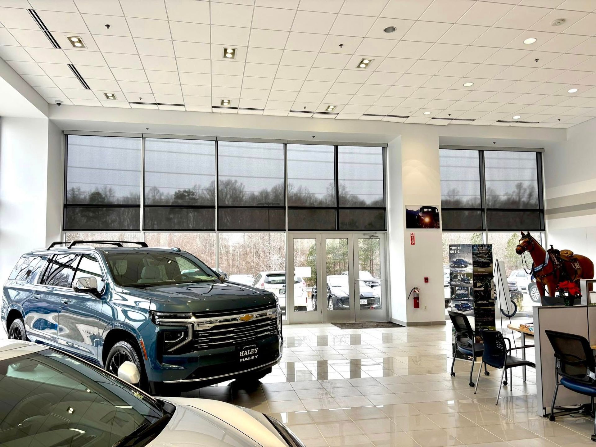 Blue SUV displayed in a bright car showroom with large windows and polished floor