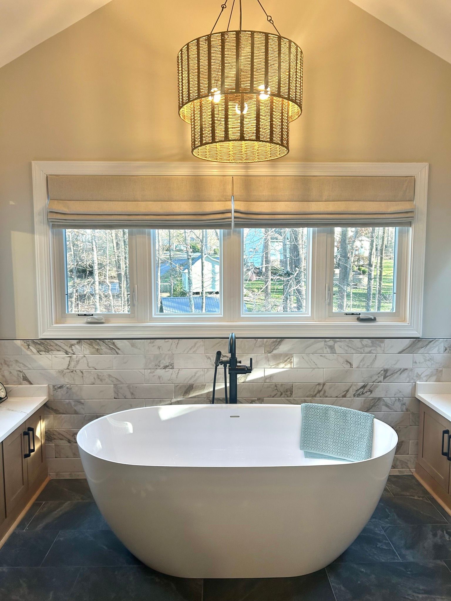 Luxurious bathroom with a freestanding tub, large window, and hanging pendant light