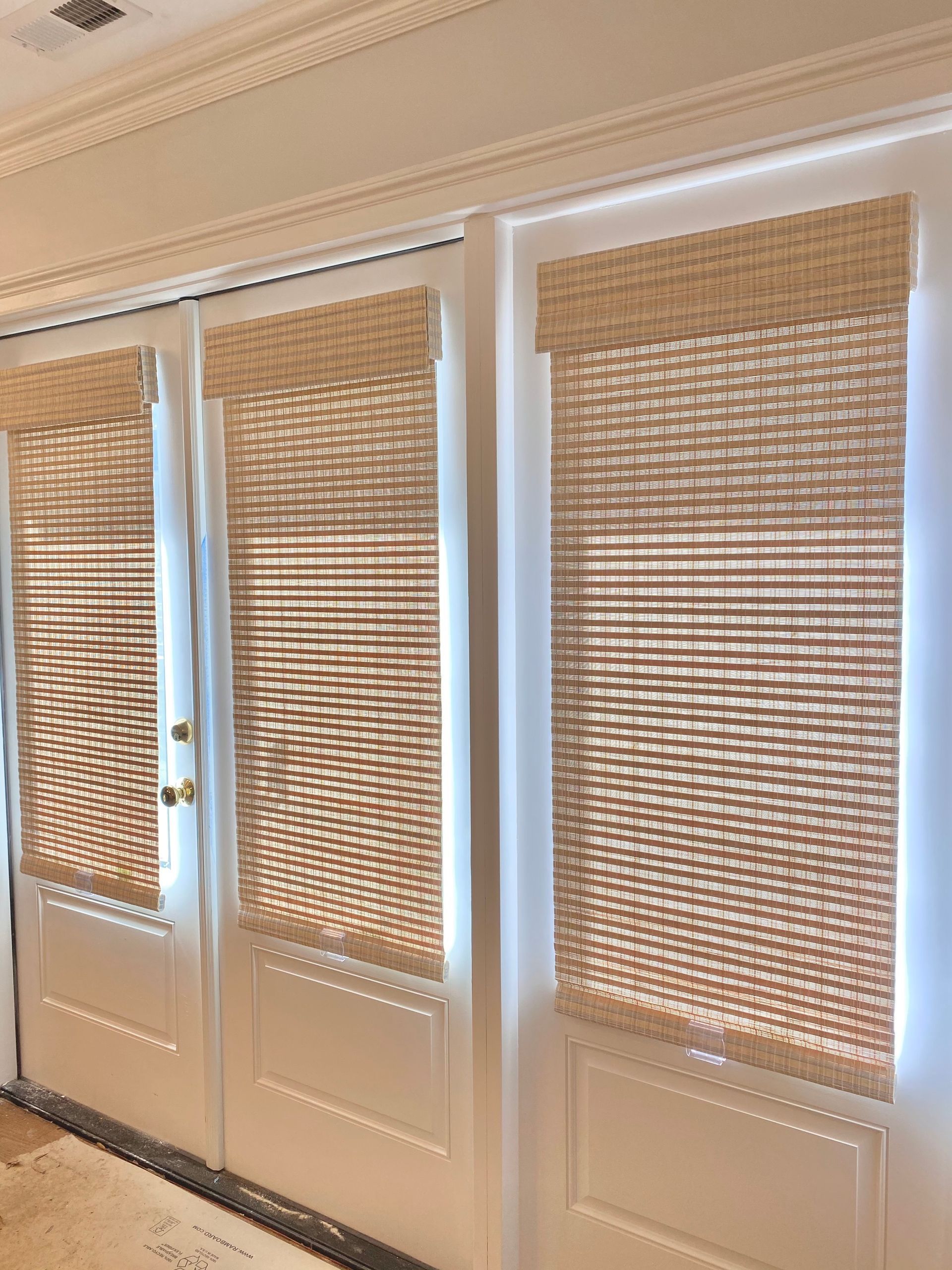 Glass double doors with woven bamboo blinds in a bright interior hallway