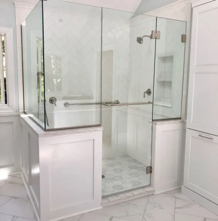 Bright white bathroom with glass shower enclosure, double sink vanity, and marble-pattern tile floor.