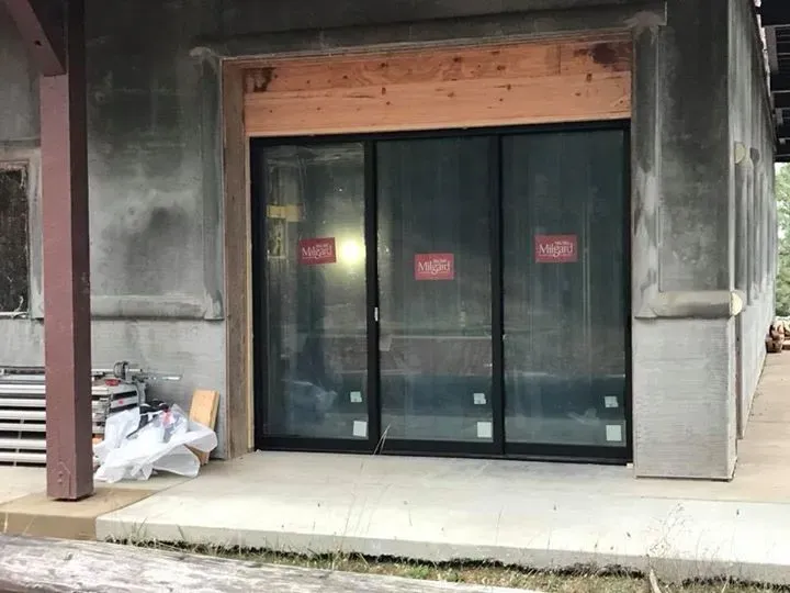 Building exterior with new black-framed glass sliding doors under construction.