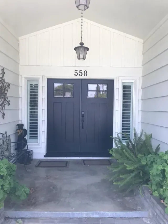 Dark blue double doors with address 558, flanked by white shutters and greenery.