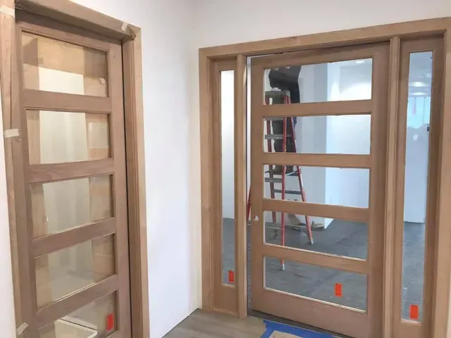 Wooden door with five glass panels, open to reveal a room with a ladder and construction materials.