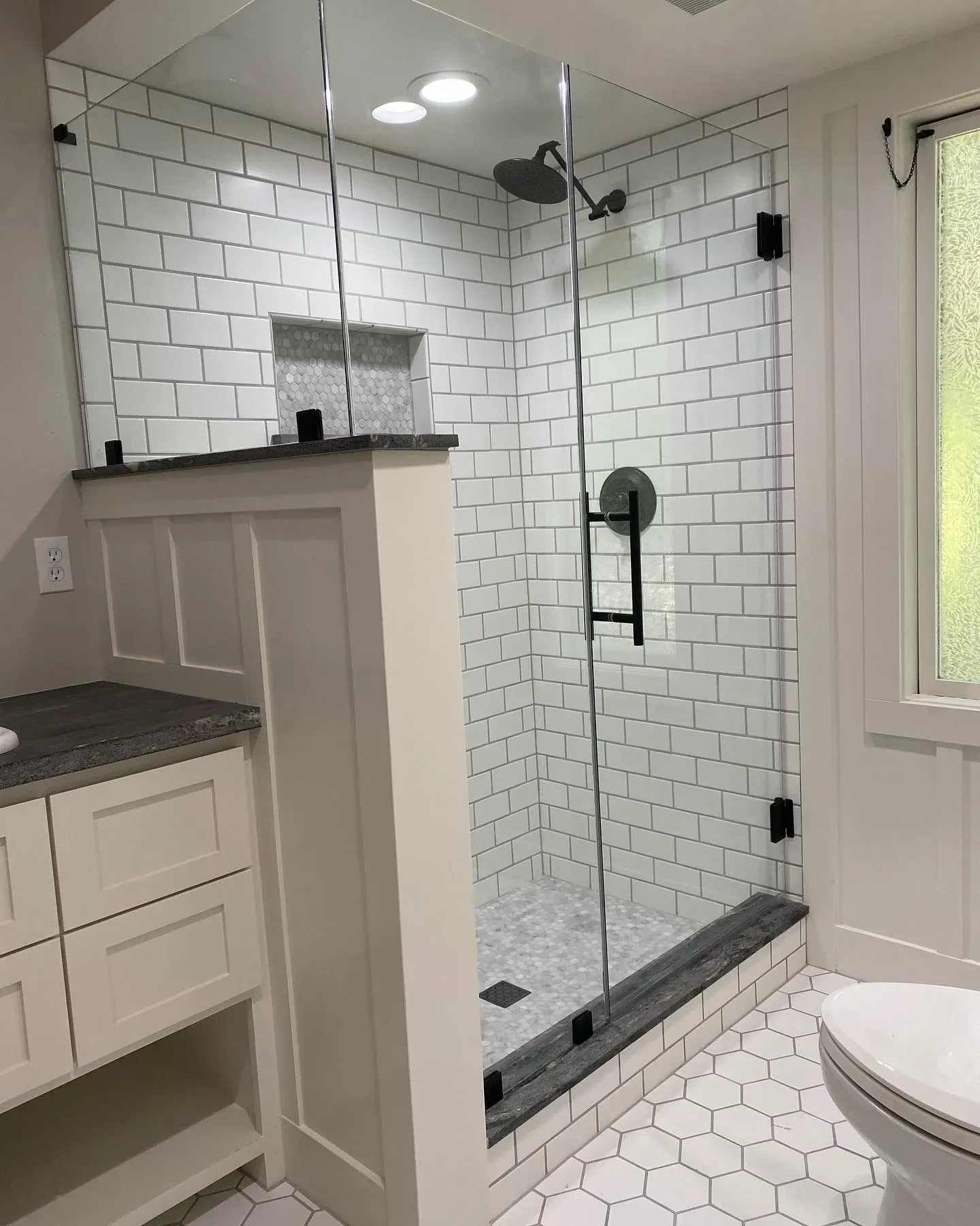 Bathroom with a glass shower, white subway tile, and a built-in vanity.