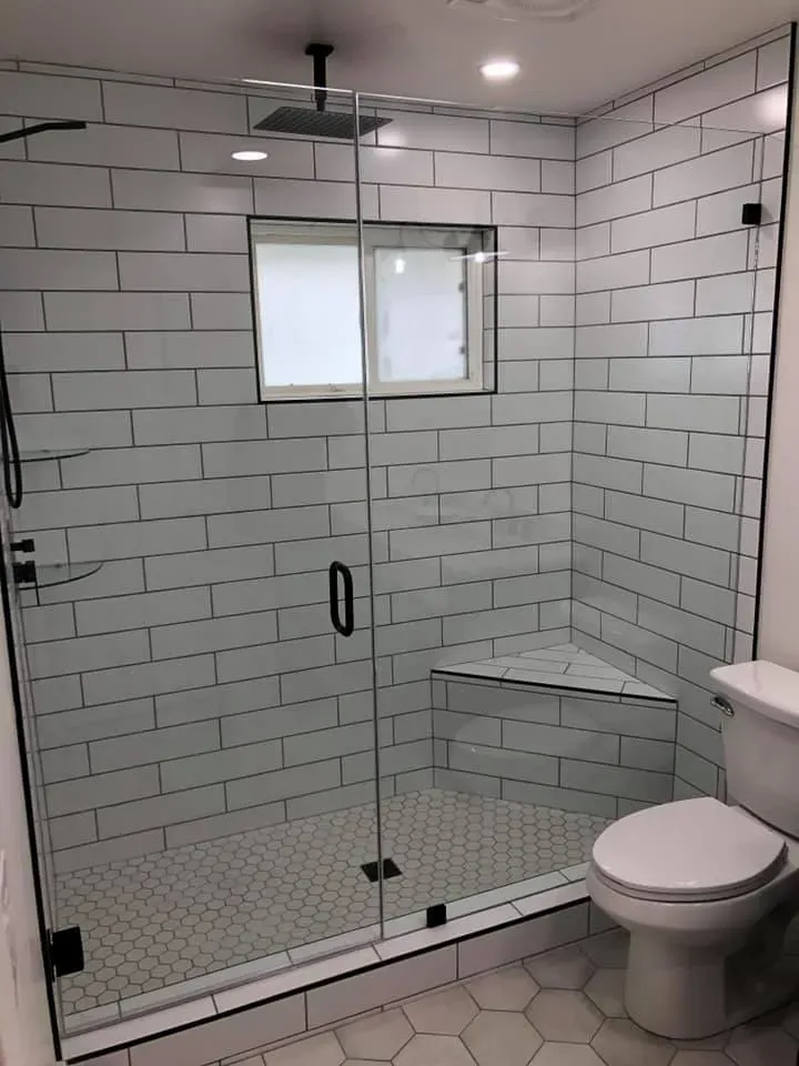 Modern bathroom with white subway tile shower, glass door, hexagon tile floor, and toilet.
