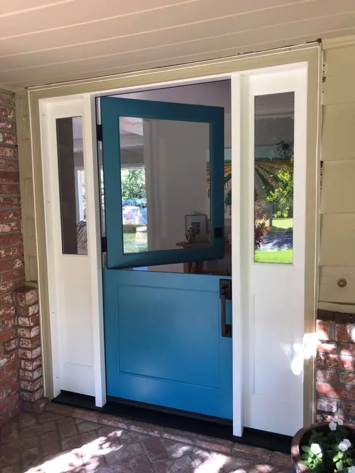 Blue Dutch door, open at the top, flanked by sidelight windows and white trim.
