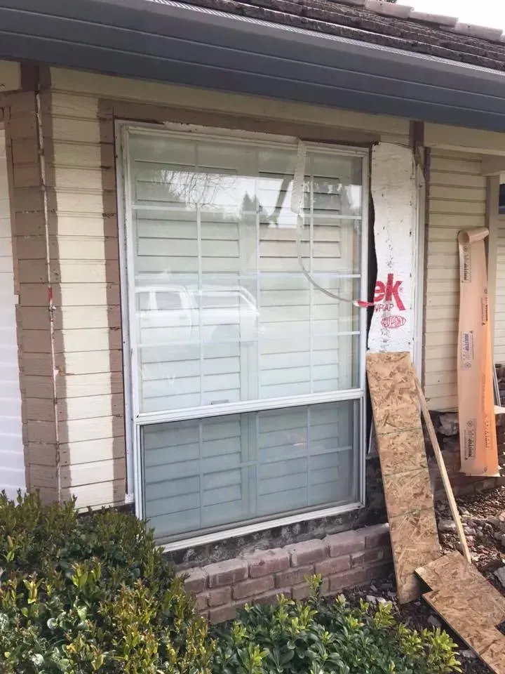 Window of a house under construction; siding partially removed, revealing sheathing.