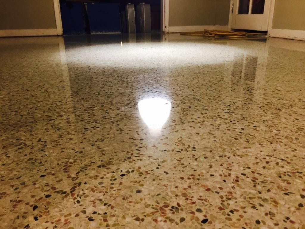 Polished speckled floor reflecting a bright light in an empty room