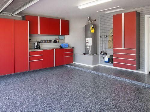 Red garage interior with red cabinets, white wall shelving, and speckled gray floor