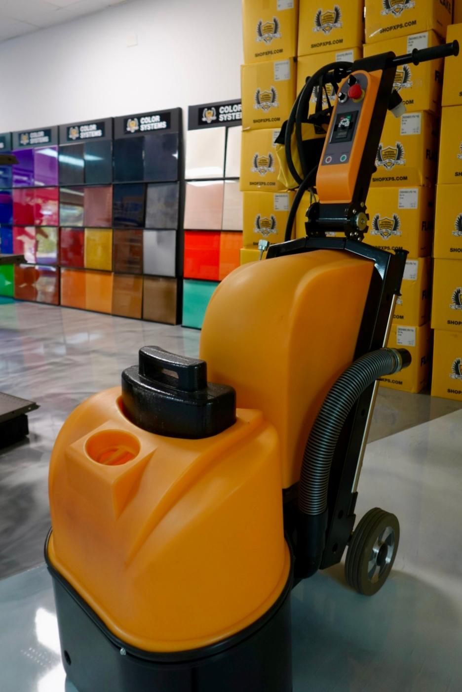 Yellow floor-cleaning machine in a showroom aisle, with stacked boxes and colorful displays in the background