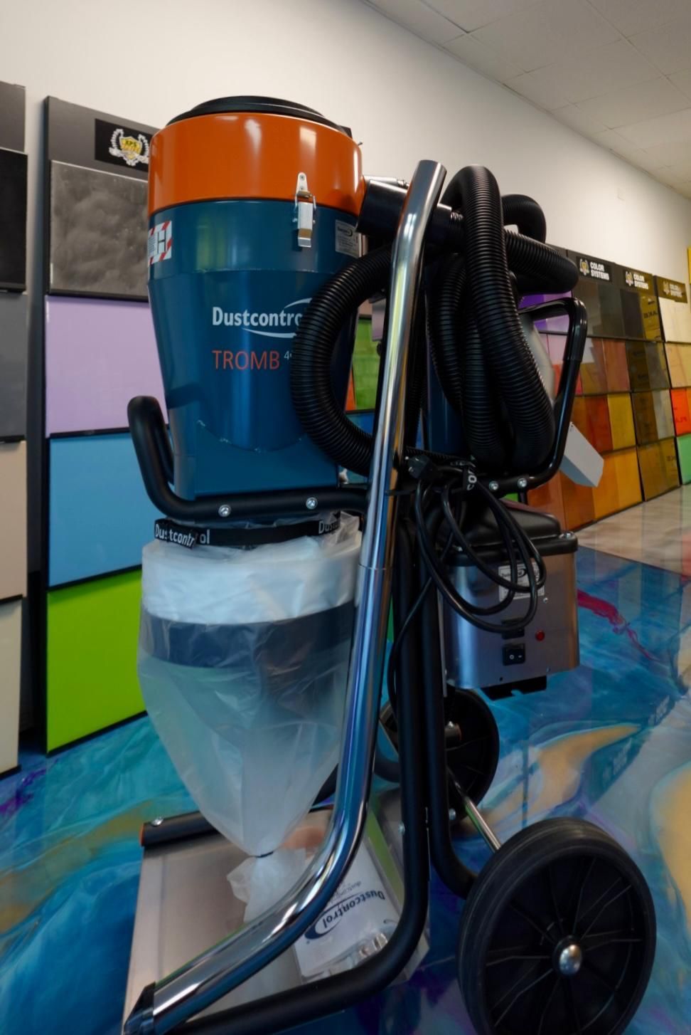 Blue-and-orange vacuum with hose and cart in a classroom storage area