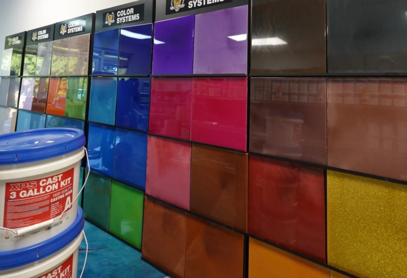 Colorful paint samples on a store display beside a white paint bucket in the foreground