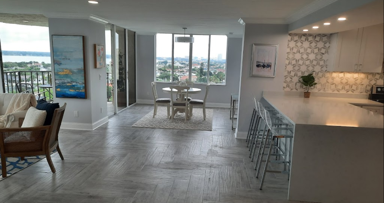 Modern open-plan kitchen and dining area with white cabinetry, large island, and city-view windows