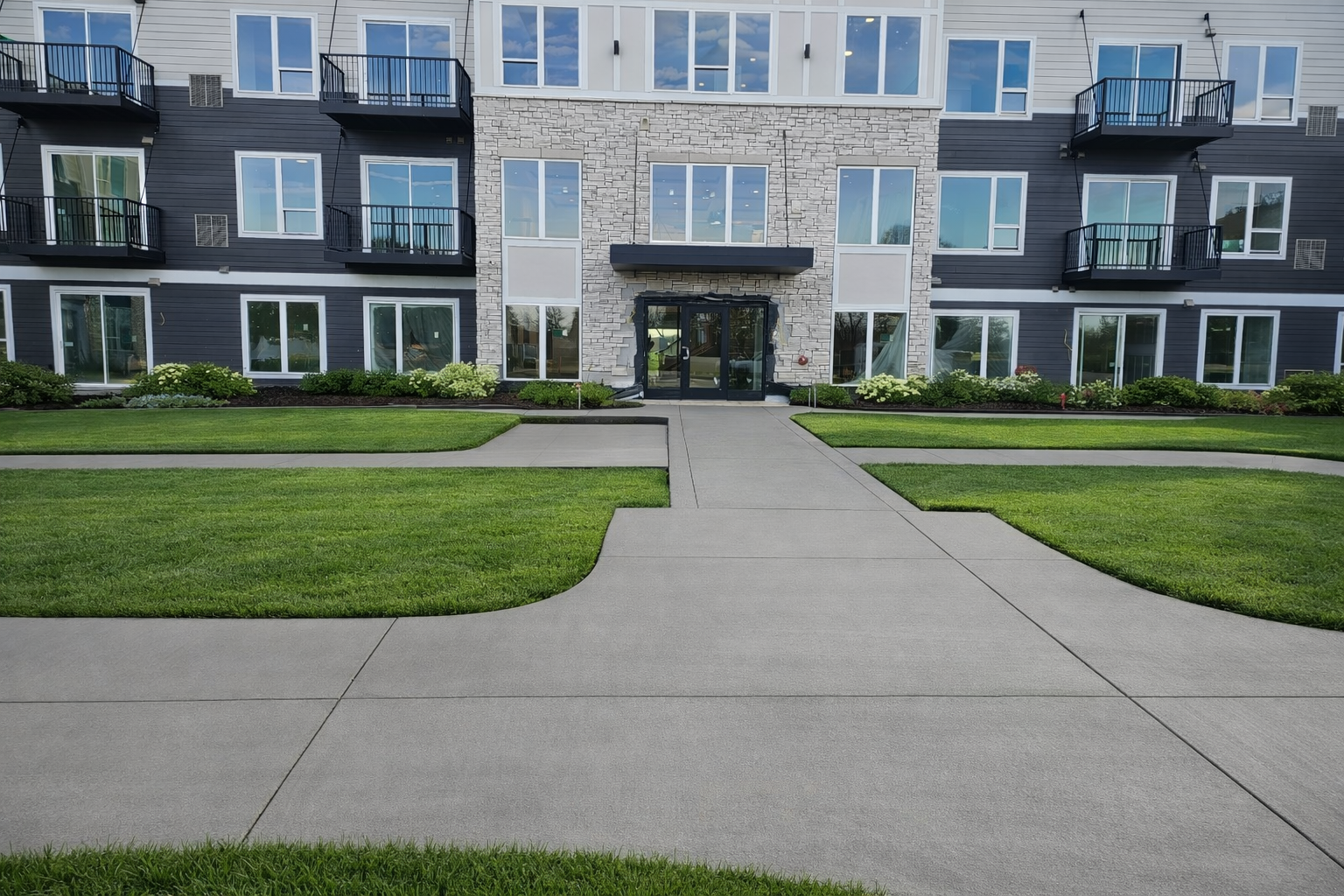 Exterior of modern building with concrete walkway and green lawn.