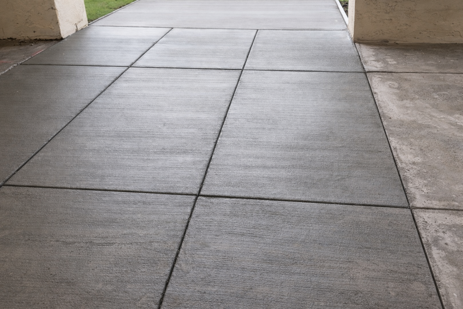 Concrete sidewalk with dark lines, under a building's overhang.