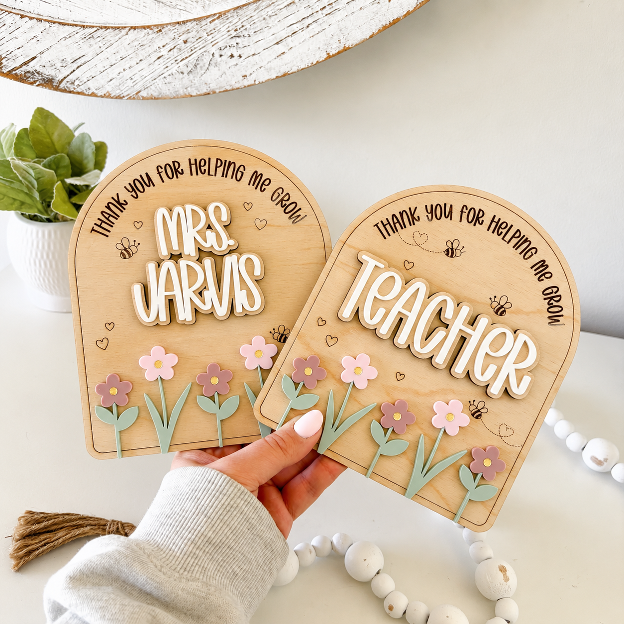 Twee beige, gepersonaliseerde kaartjes met bloemmotieven en de teksten