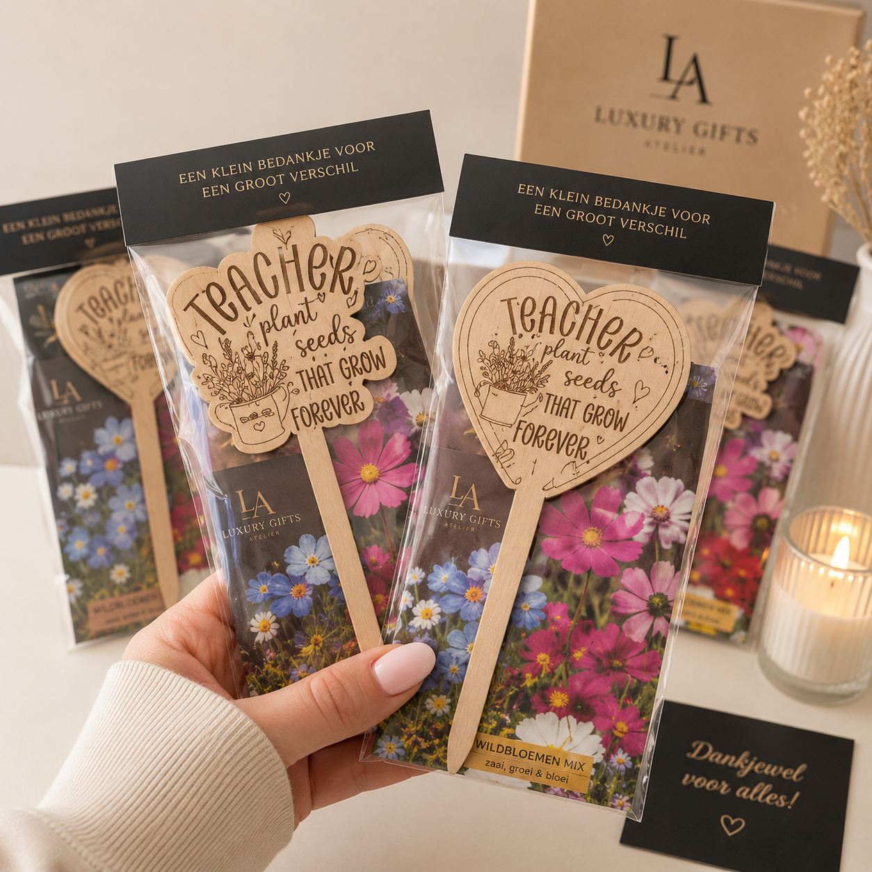 Hand met bloemencadeautasjes met hartvormige labels, voor een brandende kaars en luxe geschenkdozen.