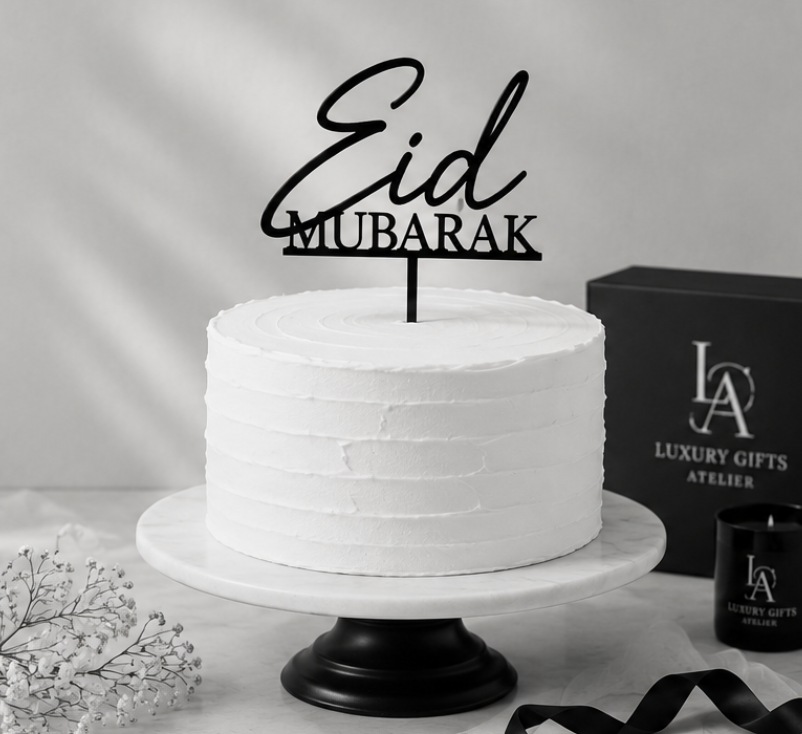 Eid Mubarak-taart met zwarte topper op een witte sokkel naast luxe geschenkdozen.