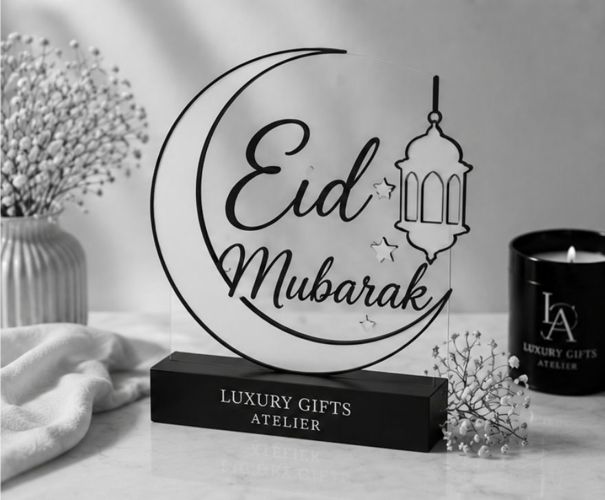 Een decoratief Eid Mubarak-bord met een halve maan en een lantaarn op een tafelblad naast kaarsen en geschenkdozen.