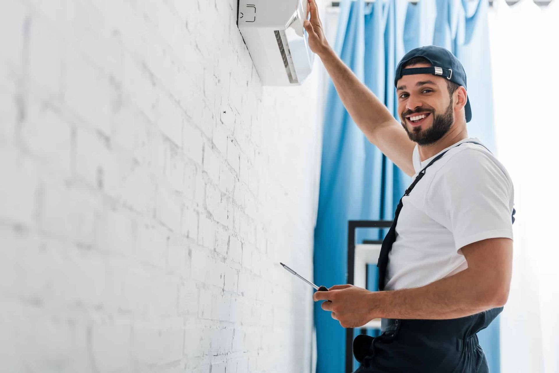 A man is installing an air conditioner on a wall.