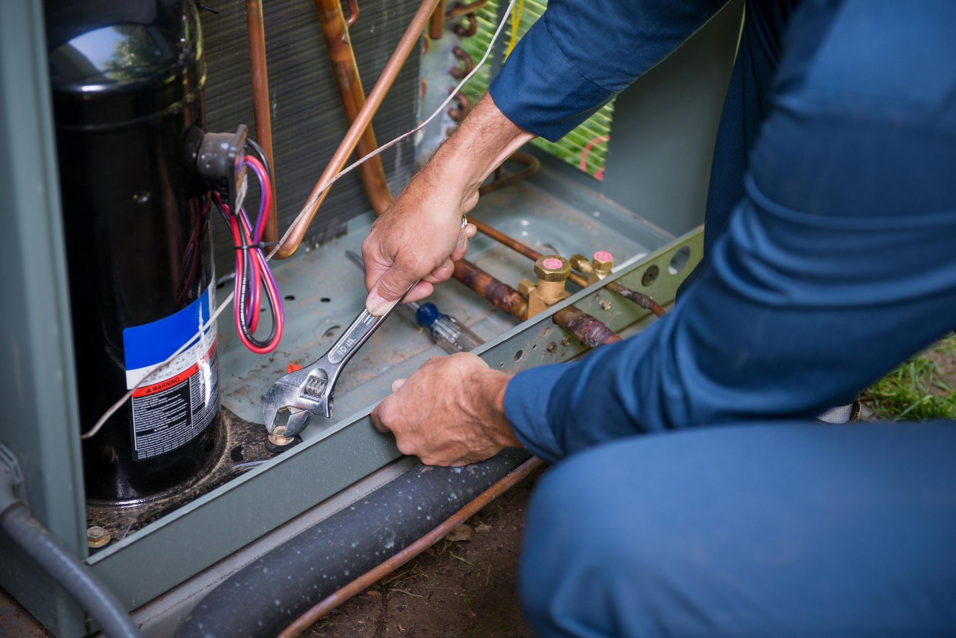 Person using a wrench to repair wiring inside an outdoor electrical cabinet