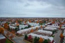 Snow-covered suburban neighborhood with rows of houses under a cloudy sky.
