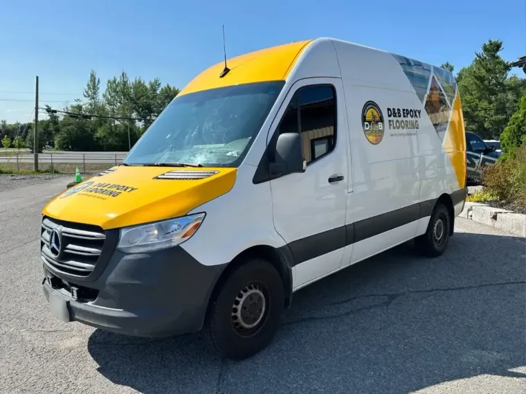 White-and-yellow service van parked outdoors on a sunny day