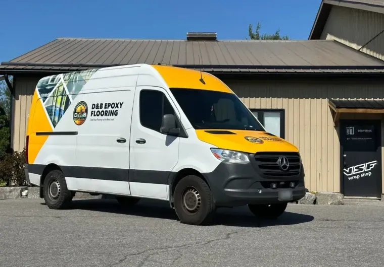 White and yellow delivery van parked outside a building on a sunny day