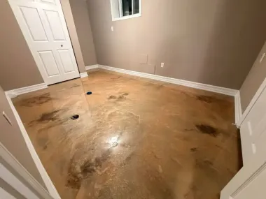 Empty beige room with stained concrete floor, white closet doors, and a small window