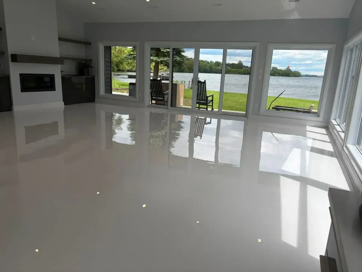 Modern empty living room with glossy white floors and large sliding doors overlooking a lake