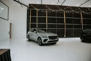 White sports car in a bright showroom with string lights and a dark display wall