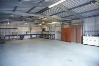 Empty metal storage warehouse with shelves, cabinets, and a concrete floor