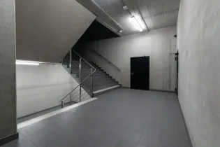 Empty concrete stairwell with metal handrails and a dark door at the back