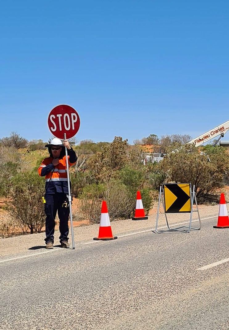 A man is holding a stop sign on the side of the road.