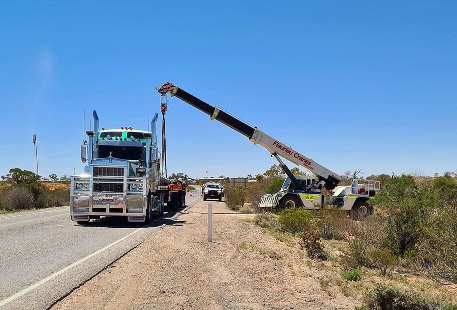A truck is being towed by a crane on the side of the road.