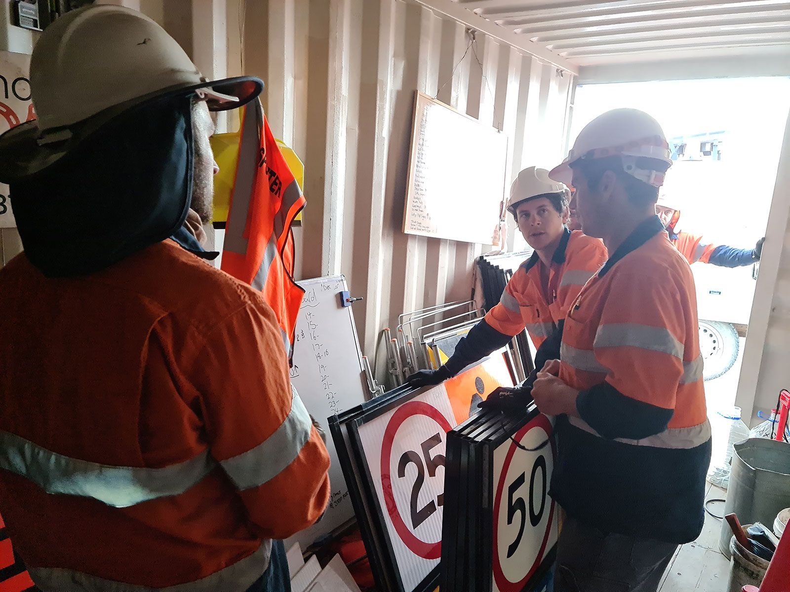 A group of construction workers are standing in a room holding signs.