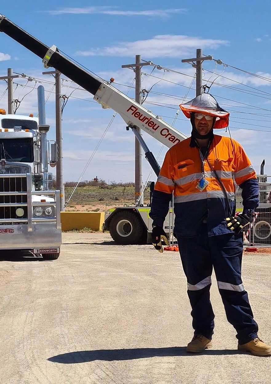 A man is standing in front of a truck with a crane attached to it.