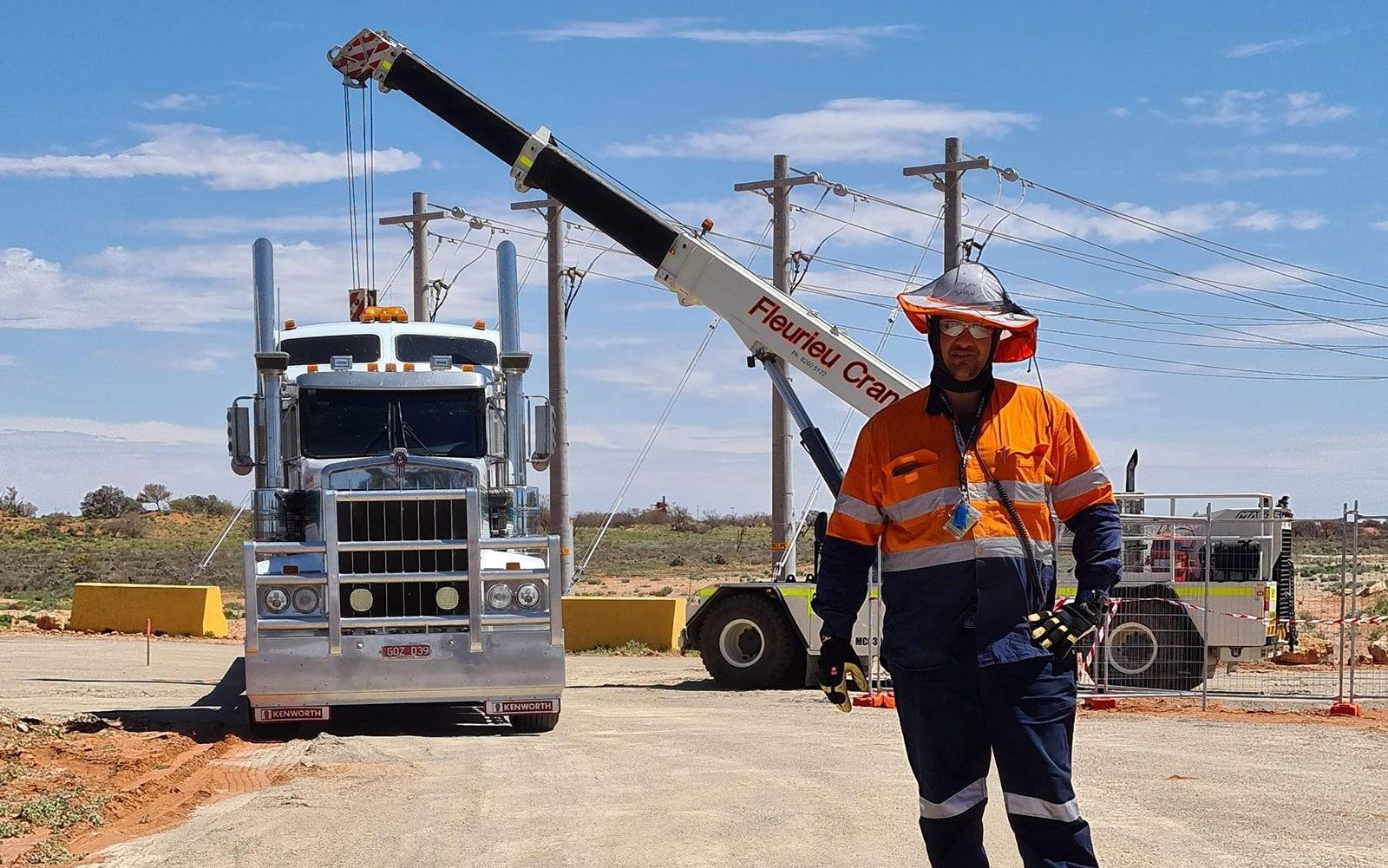 A man is standing in front of a truck with a crane attached to it.