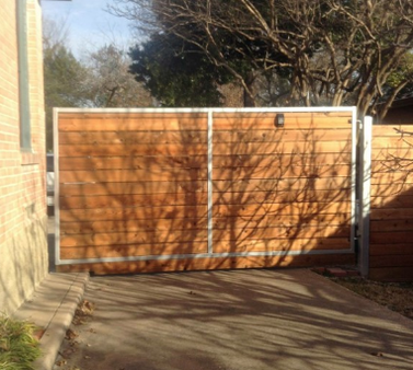 A wooden gate is sitting in front of a brick building.