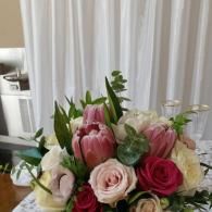 Pink and white rose bouquet with tulips on a table in front of white curtains