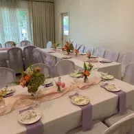 Decorated banquet table with lavender napkins and floral centerpieces in a bright room