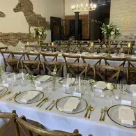 Elegant banquet hall with long white-clothed tables, gold chairs, and neatly set place settings