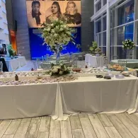 Elegant dessert buffet with a tall floral centerpiece and framed portrait display in a bright indoor venue