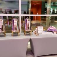 Buffet table with covered trays and a sign in a bright lobby or banquet hall