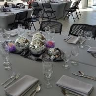 Set dining table with napkins, glasses, cutlery, and silver balloon centerpieces in a banquet hall