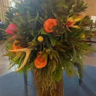 Tropical floral arrangement with orange and yellow blooms in a tall vase