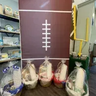 Bundled household items in plastic bags beside a maroon wall with a white ladder-like design